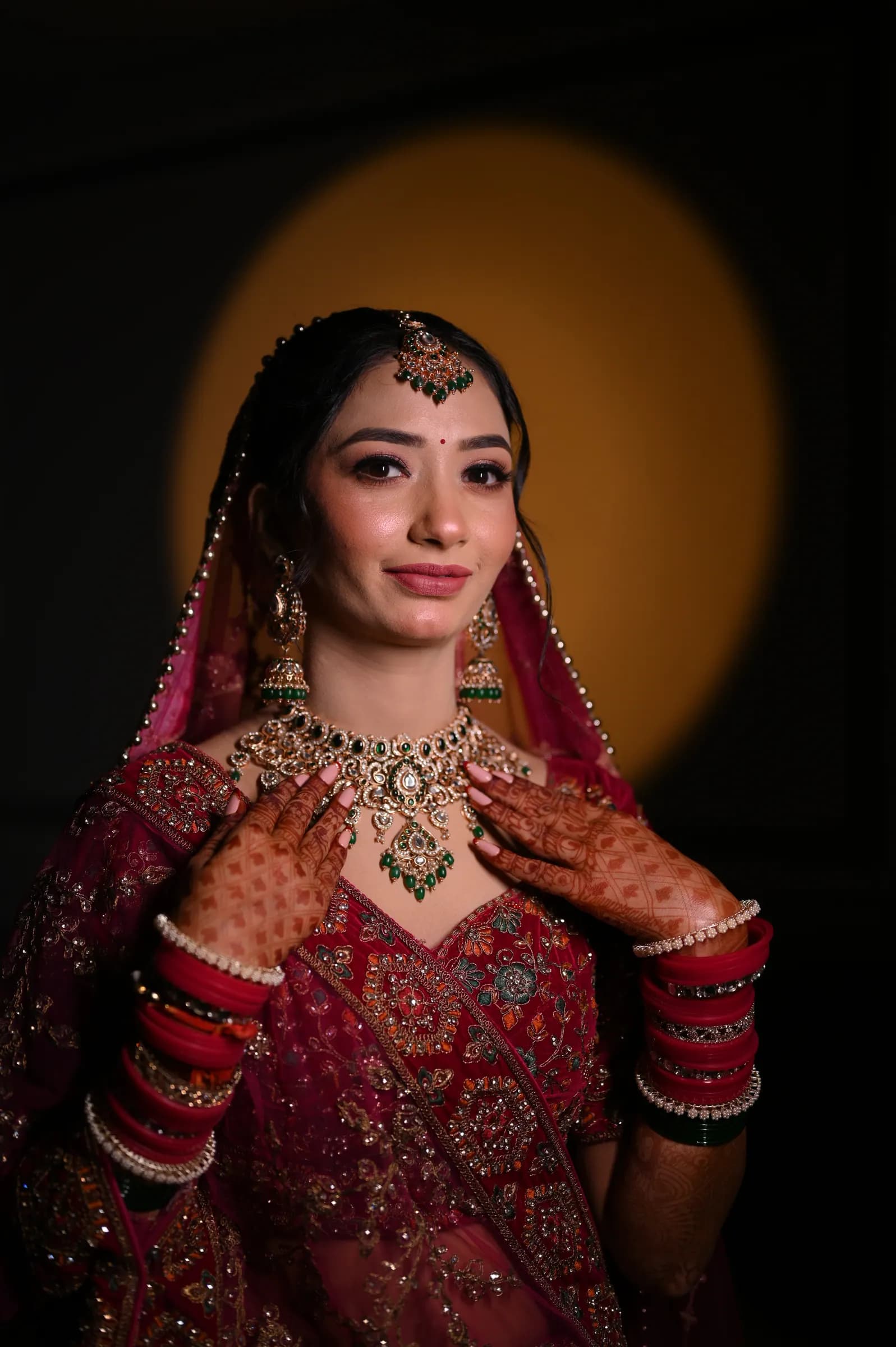 Bride touching her necklace in front of a warm circular light