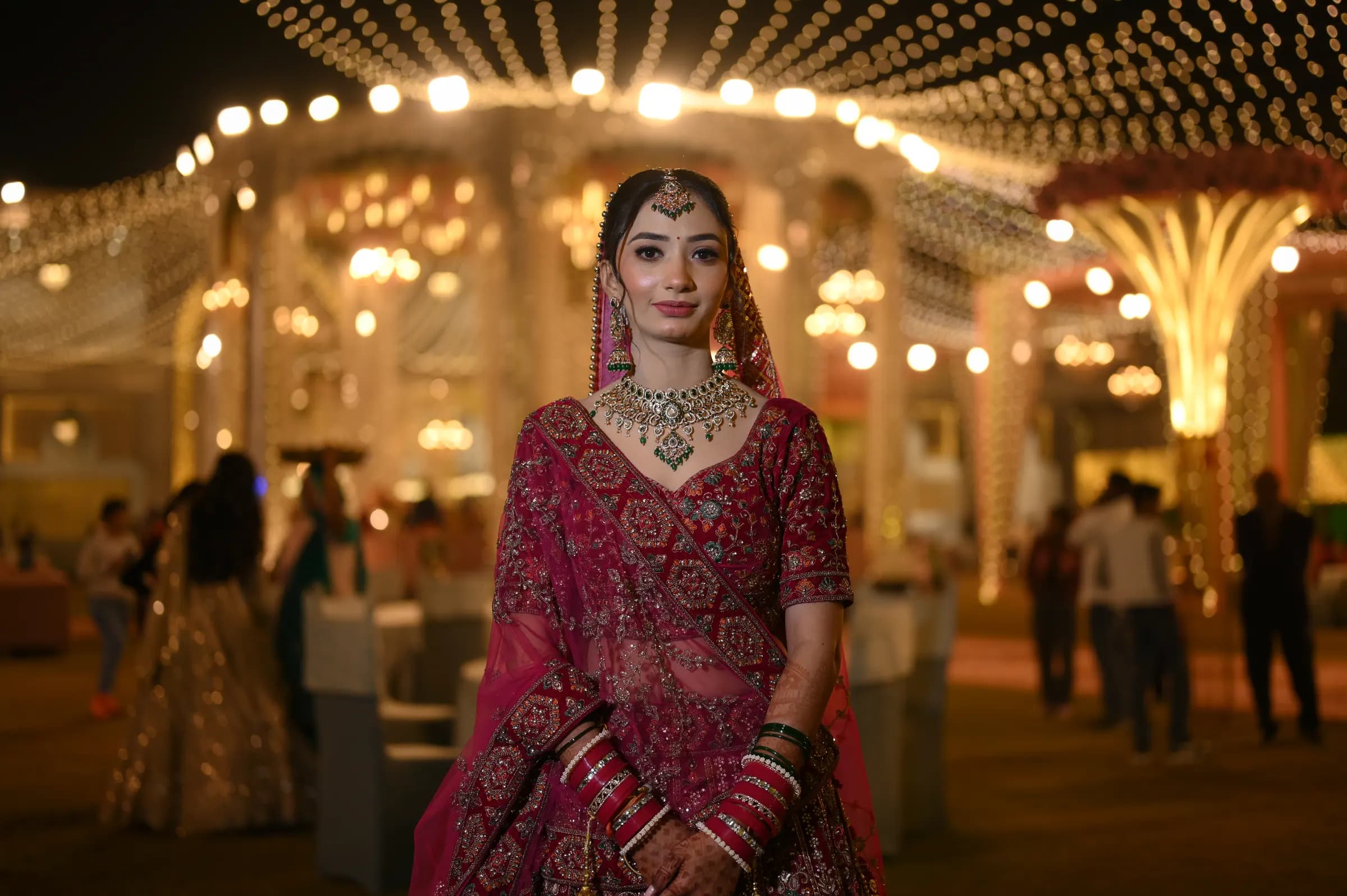 Bride standing in a wedding venue lit with hanging fairy lights at night