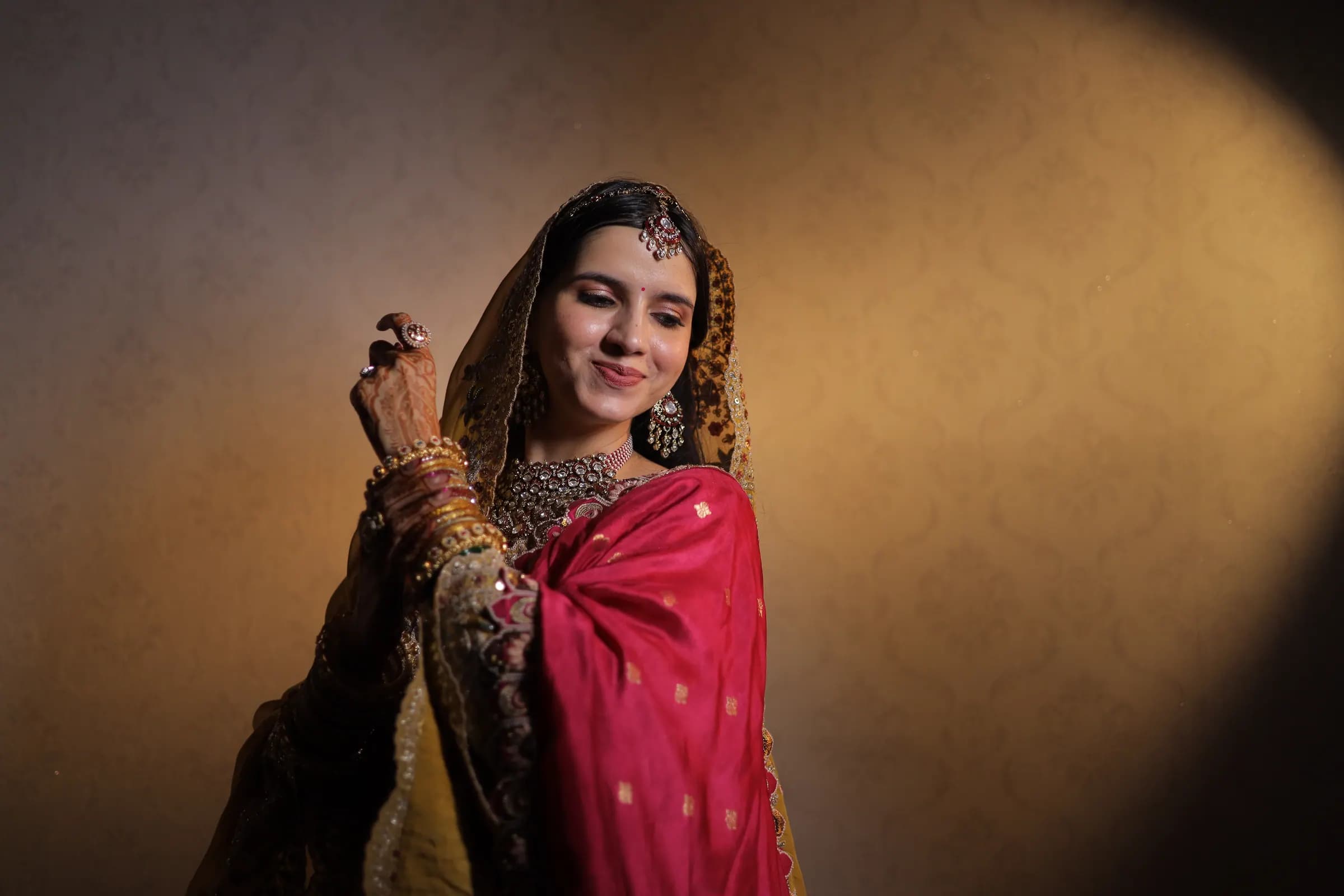Bride in a pink and yellow traditional odhni under a warm spotlight