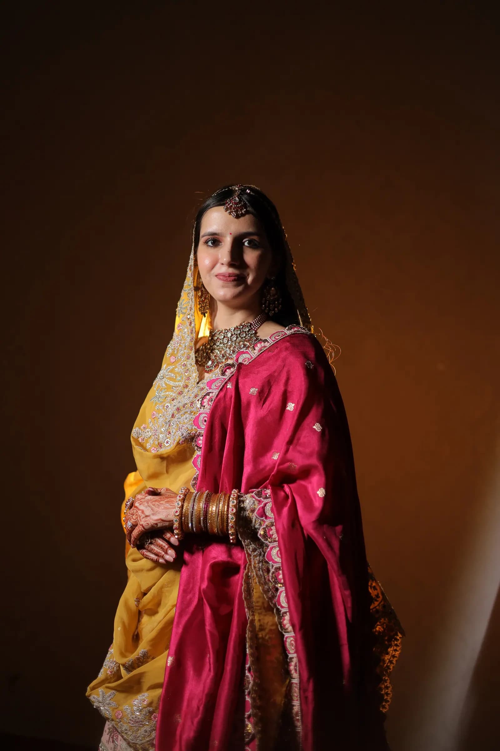 Full-length portrait of a bride in a pink and yellow traditional outfit