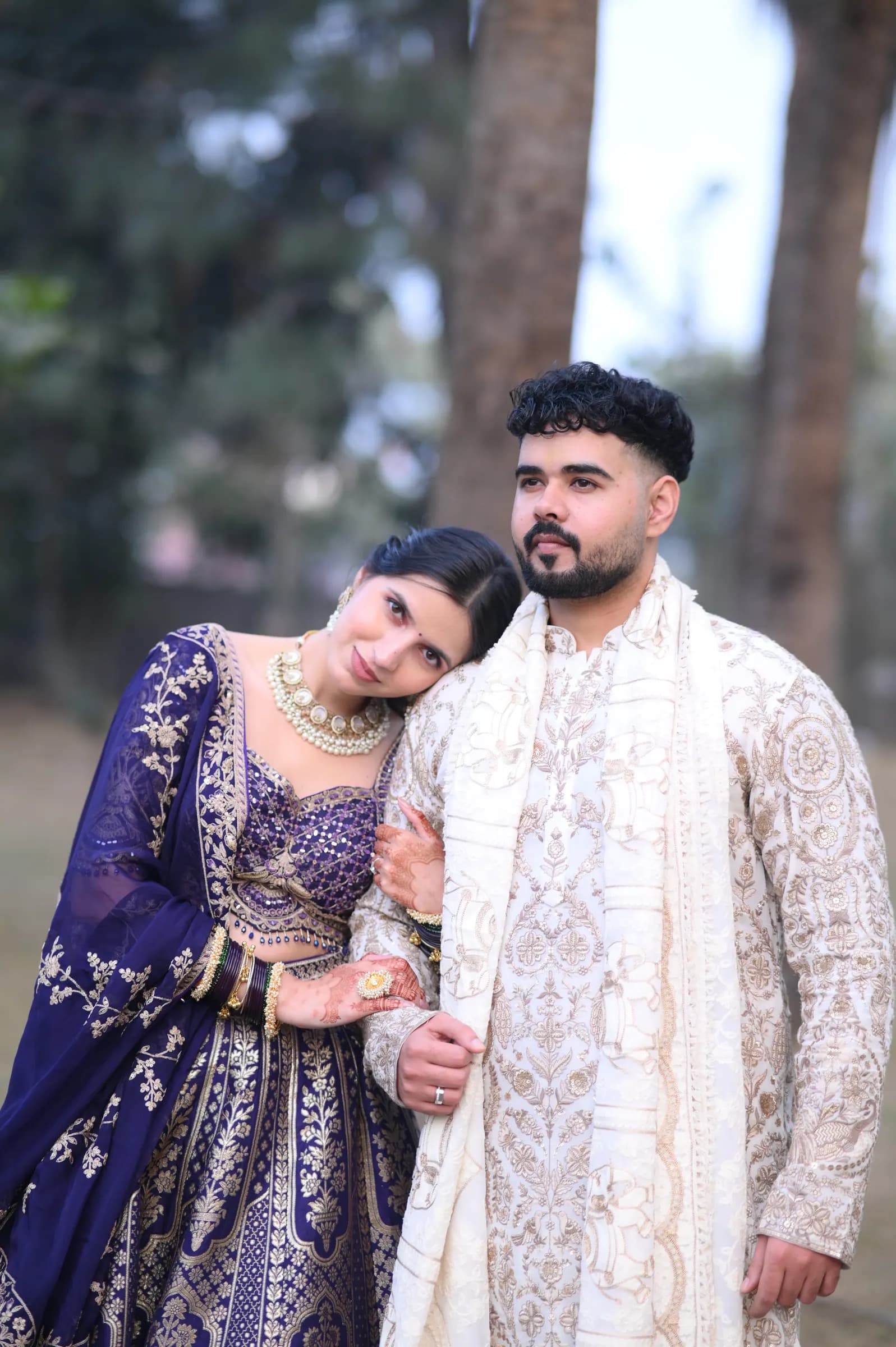 Couple leaning into each other outdoors among tall trees during a pre-wedding shoot