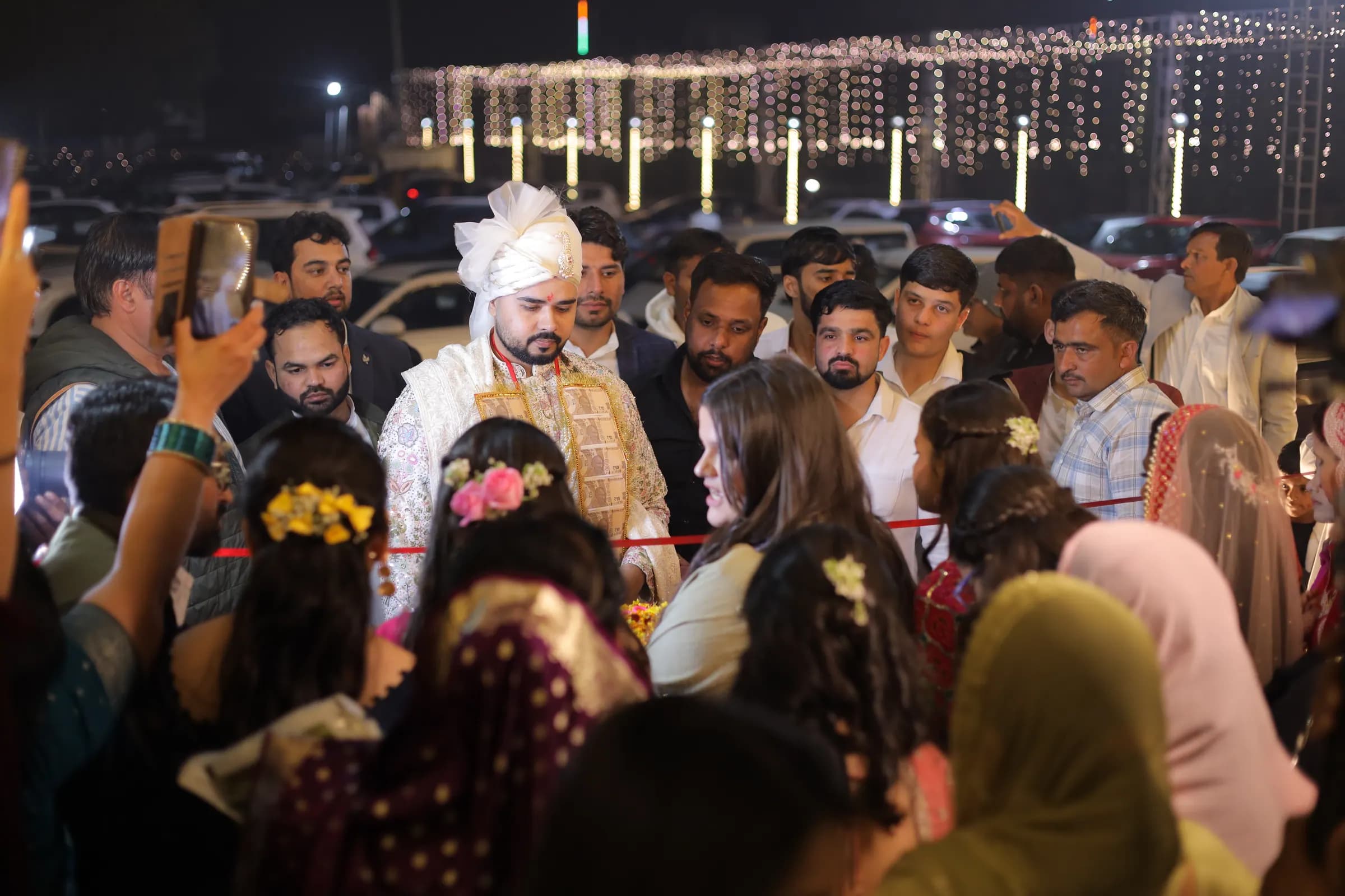 Groom surrounded by family during the ribbon ritual at the venue entrance
