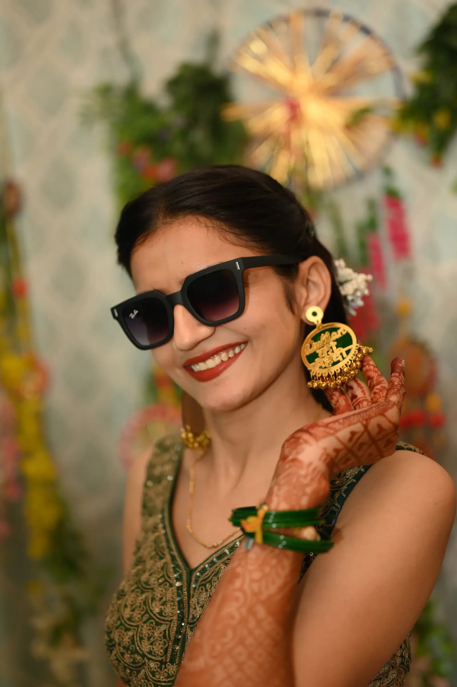 Candid of a smiling bride in sunglasses showing her mehendi