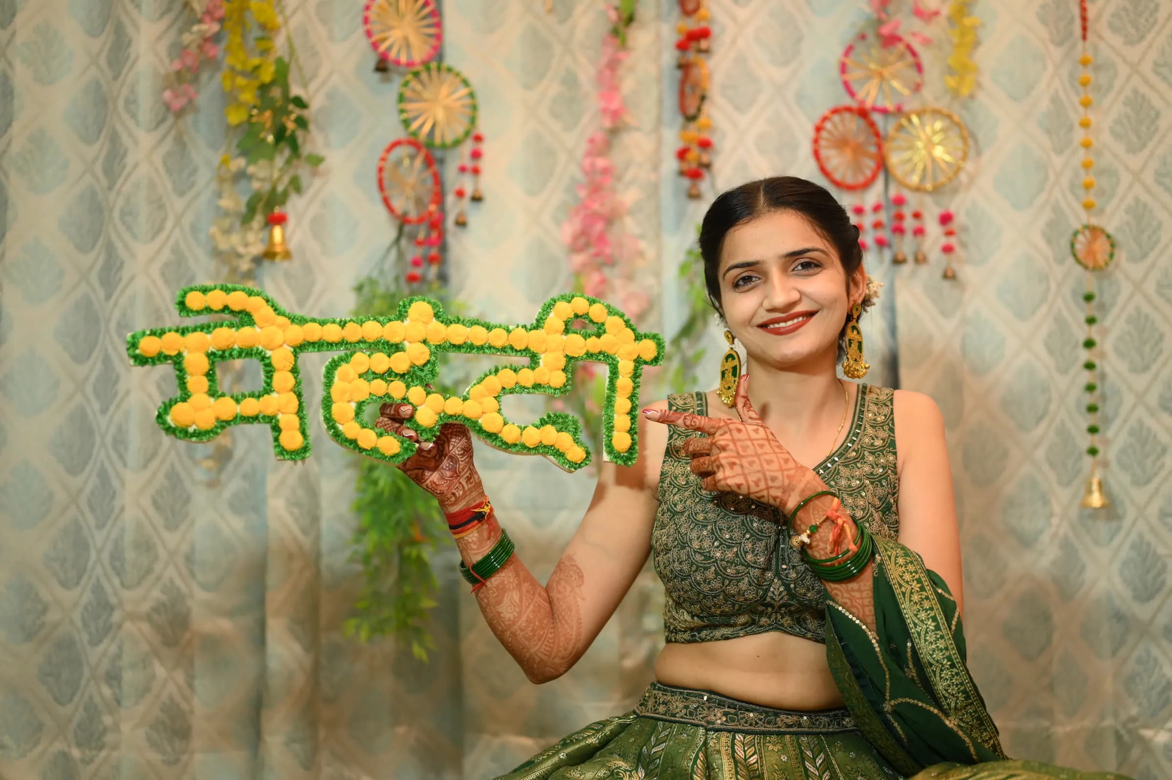 Bride with a floral मेहंदी sign at her mehendi function